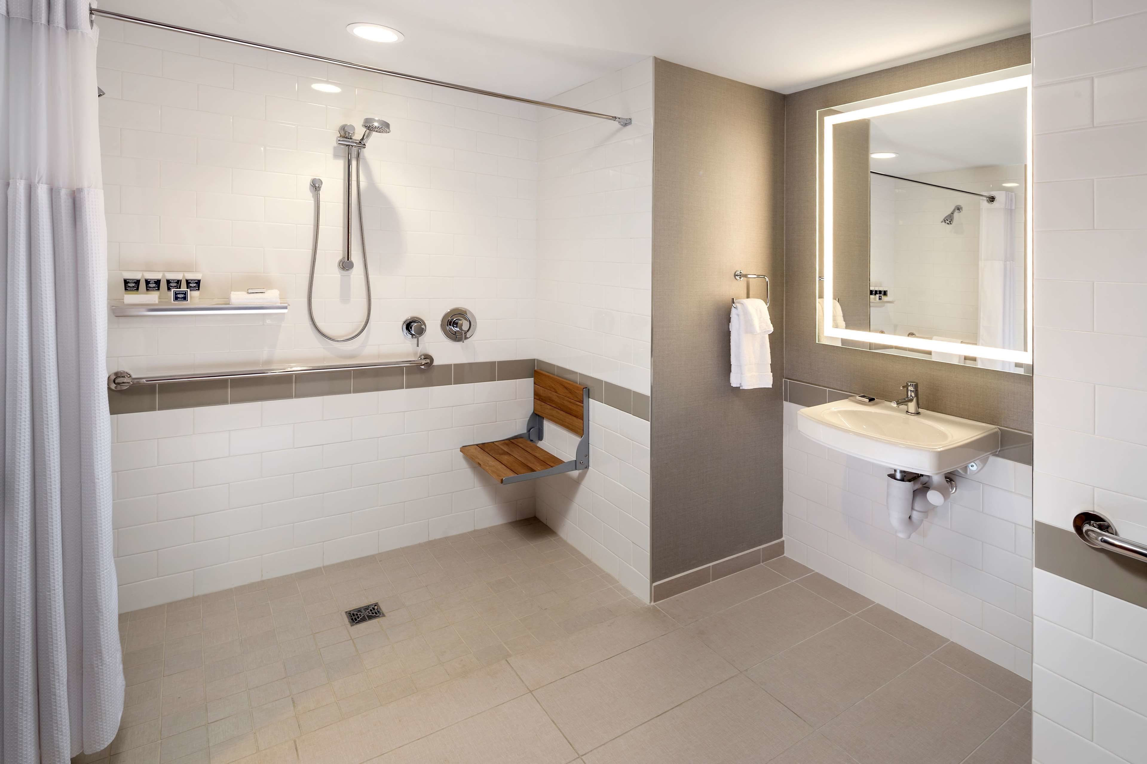 A modern bathroom with a shower, a sink, and a mirror.