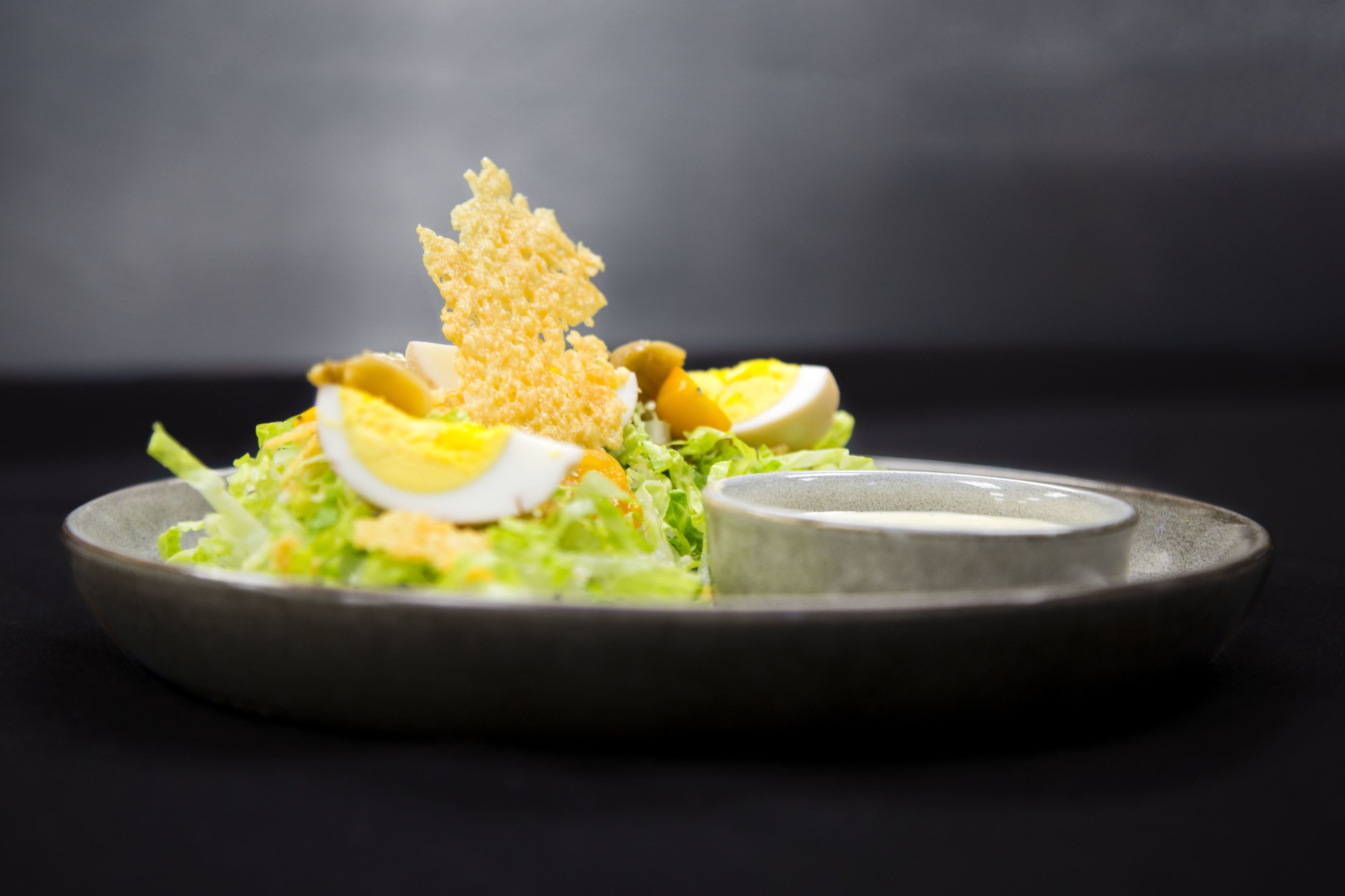 Ensalada con lechuga, huevos y un topping crujiente sobre un plato.