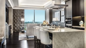 A modern kitchen with a large island, dark cabinetry, and a view of the city. - The Post Oak Hotel at Uptown Houston (Houston)