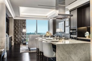Uma cozinha moderna com uma ilha grande, armários escuros e vista para a cidade.