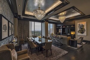 A spacious living area with a large dining table, comfortable seating, and a view of the city.