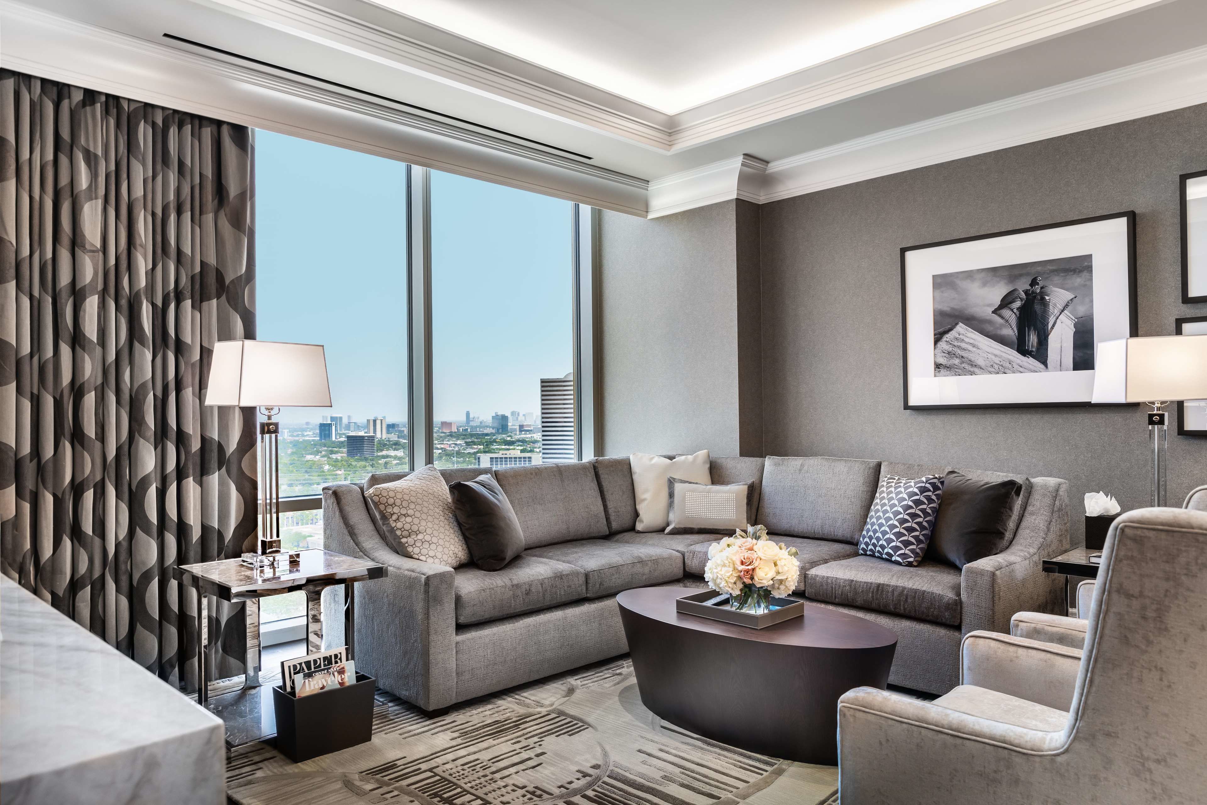 A modern living room with a sectional sofa, a coffee table, and a city view through large windows.