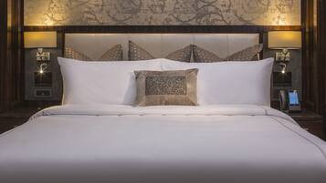 A hotel room with a large bed, a headboard with a patterned design, two bedside lamps, and a control panel on the nightstand.