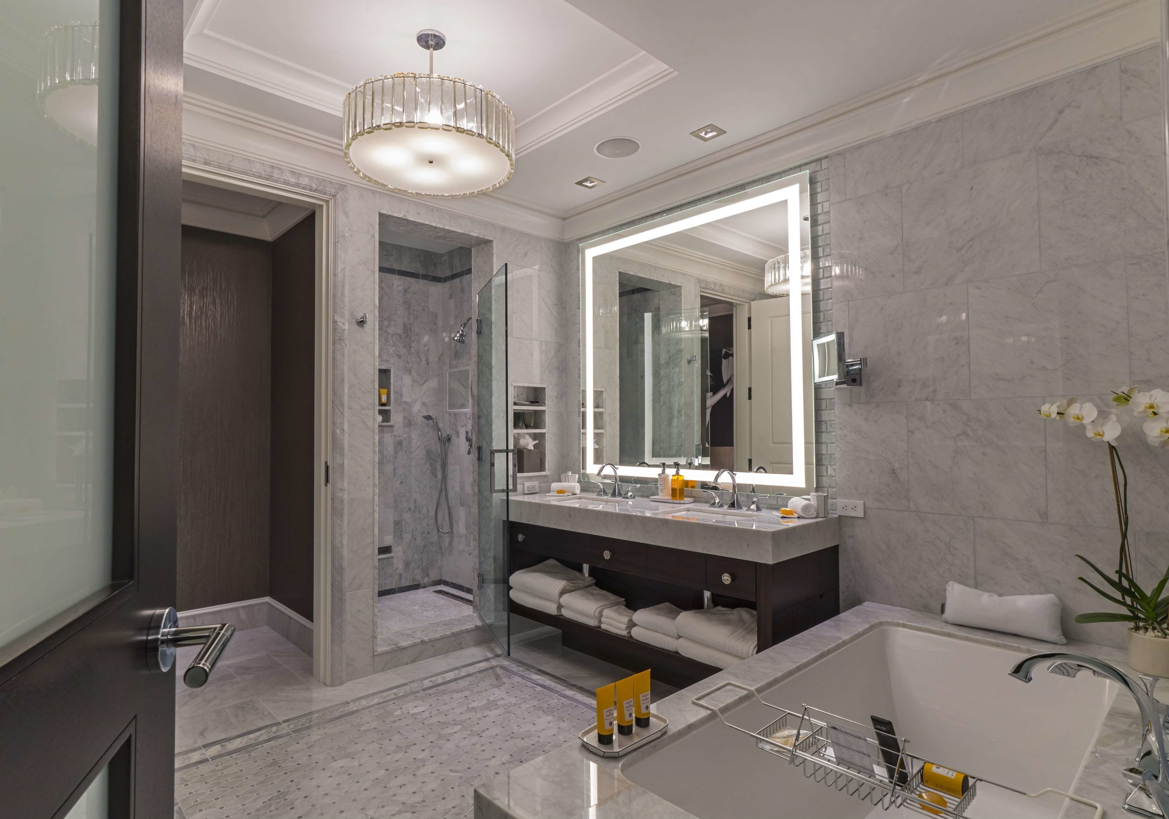 A modern bathroom with a large mirror, a bathtub, and a shower area.