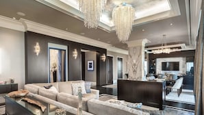 A modern living room with a sofa, glass coffee table, and a chandelier. - The Post Oak Hotel at Uptown Houston (Houston)