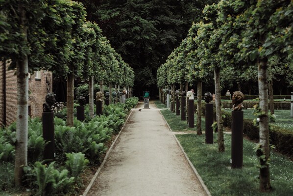 A pathway flanked by trees and sculptures, leading to a distant point.