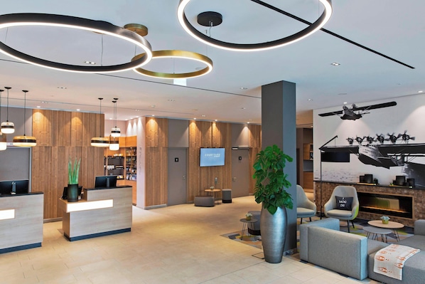 Un moderno vestíbulo de hotel con mostrador de recepción, zona de estar y una pantalla grande que muestra 'COURTYARD'.