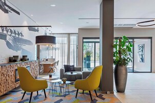 Um lobby moderno com balcão de recepção, área de estar e amplas janelas.