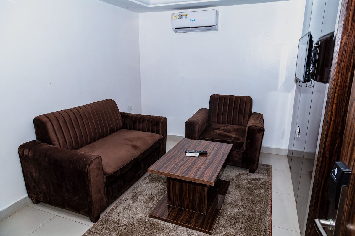 Ein Wohnzimmer mit einem braunen Sofa, einem passenden Sessel und einem Holztisch.