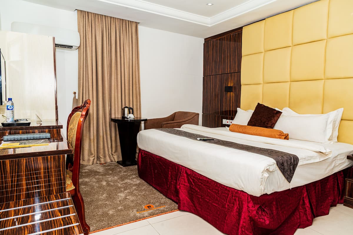 Ein Hotelzimmer mit einem Bett, einem Schreibtisch, einem Stuhl, einem Kleiderschrank und einem Vorhang.