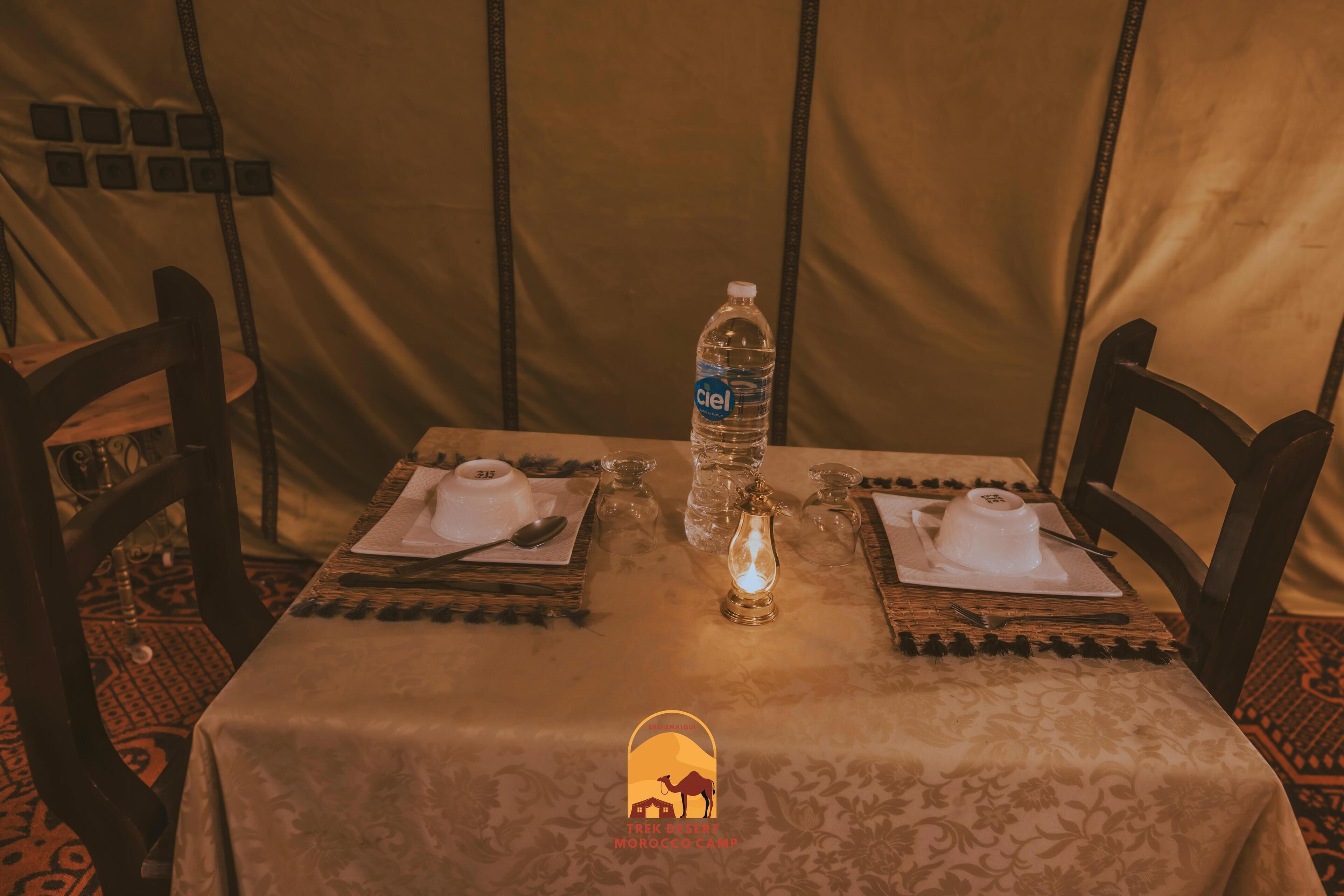 A table set for two with a bottle of water, a candle, and a menu.
