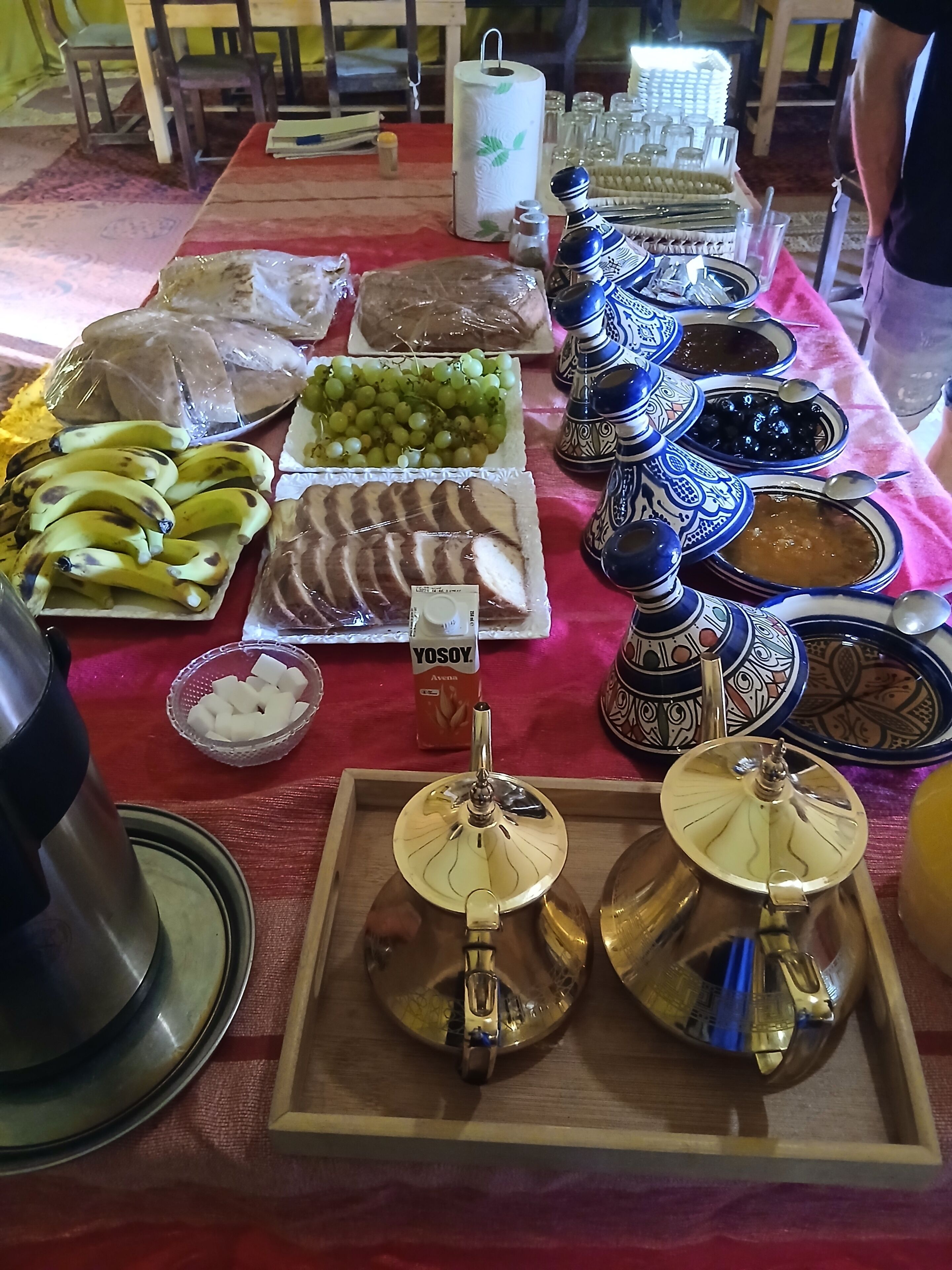 A table with various food items and traditional Moroccan tea pots.
