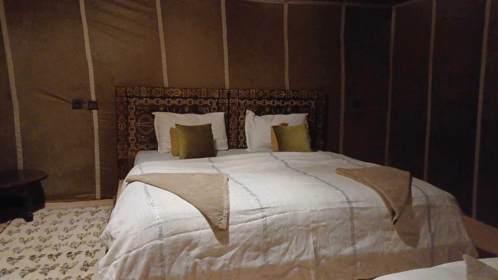 Un letto con una testiera decorata, una coperta bianca e due cuscini.