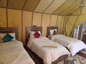 A room with three beds, each with a headboard and pillows, under a tent-like structure.