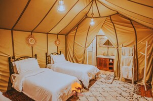 Una habitación con carpa, dos camas, una mesita y una lámpara colgante.