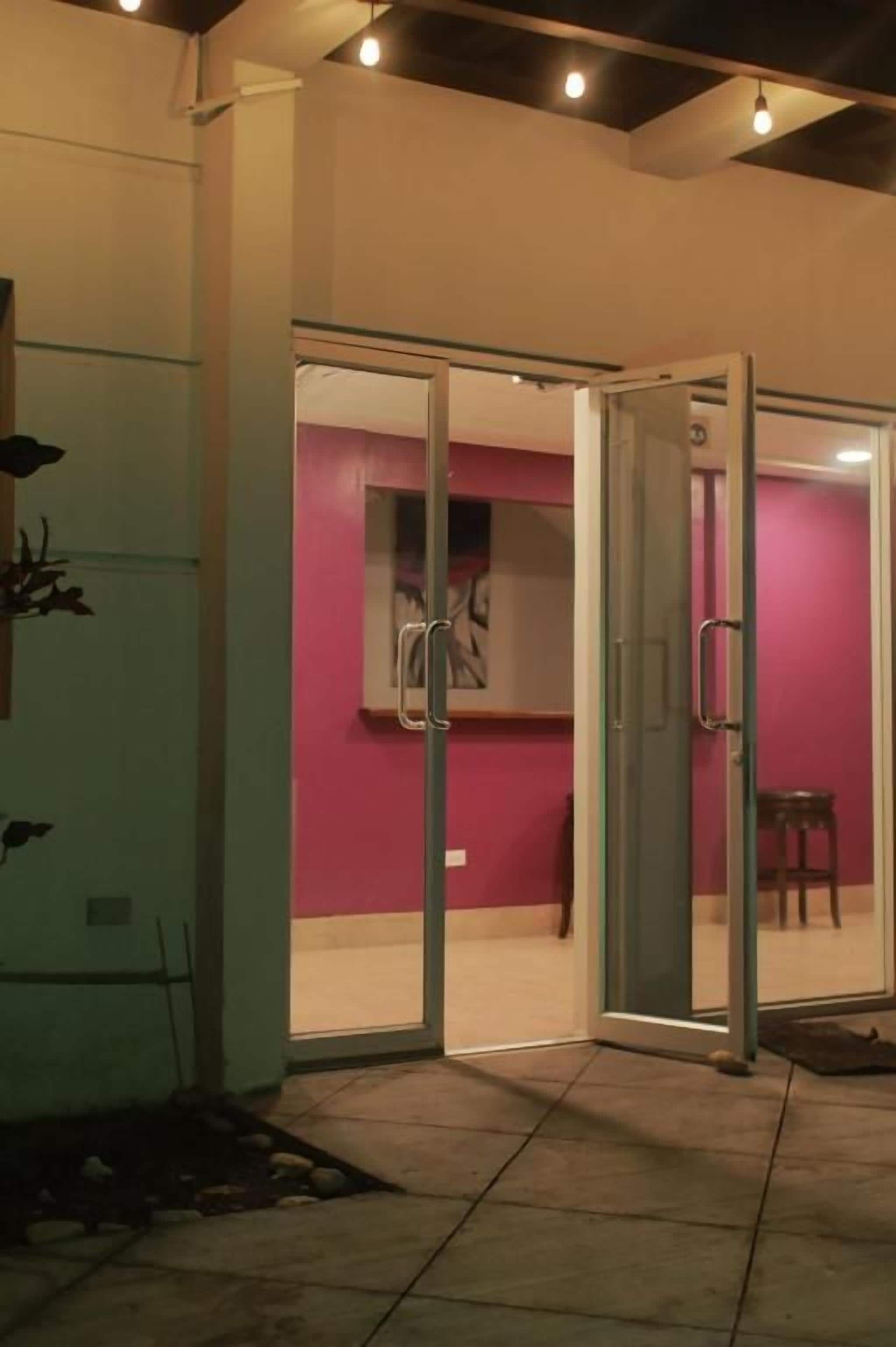 A hotel room with a sliding glass door leading to a pink wall and a visible bathroom.