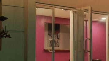 A hotel room with a sliding glass door leading to a pink wall and a visible bathroom.