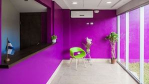 A modern reception area with a purple wall, a green chair, and potted plants. - Airport Inn Managua (Managua)