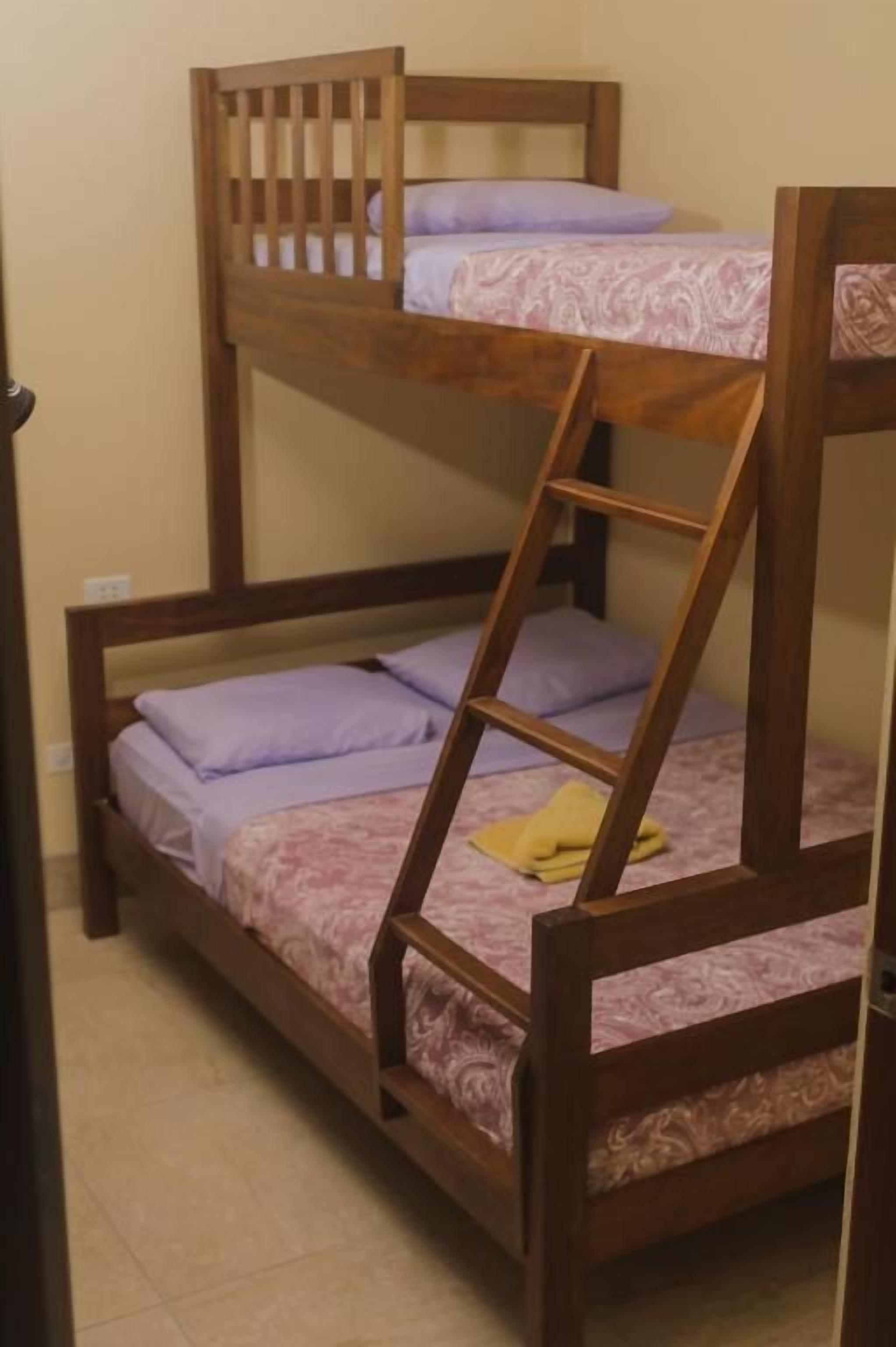 Una cama litera con escalera, cabecero de madera y cubrecama estampado.