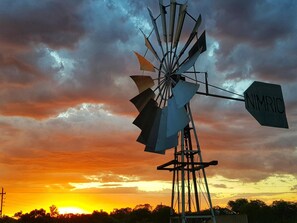 A windmill with a sign that reads "NIMRIC" against a sunset sky.