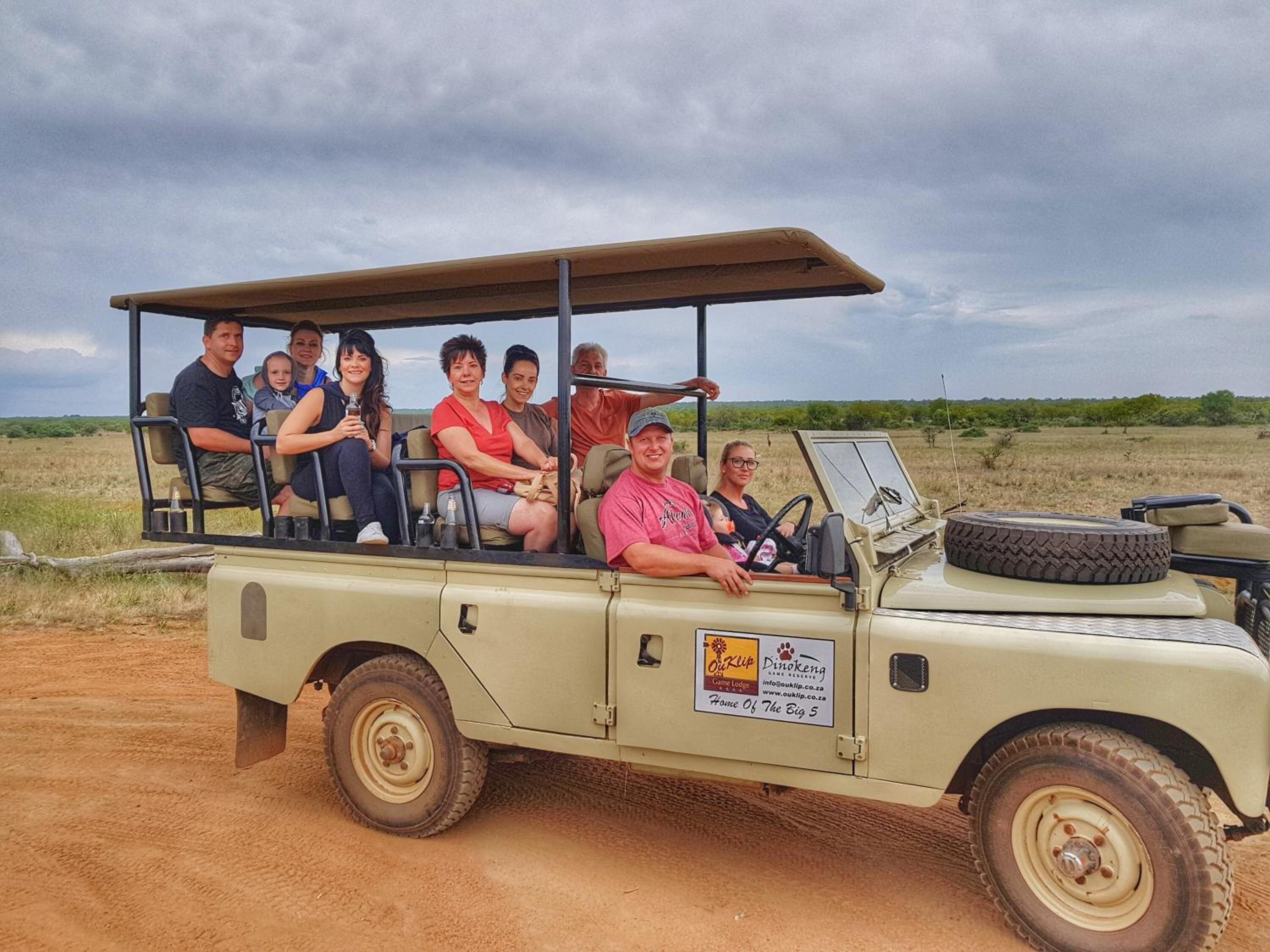 En safaribil med tak, ett reservdäck och en skylt som annonserar för ett safarilodge.