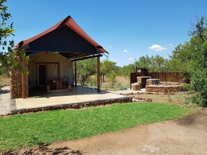 A rustic outdoor structure with a covered patio, stone walls, and a small seating area.