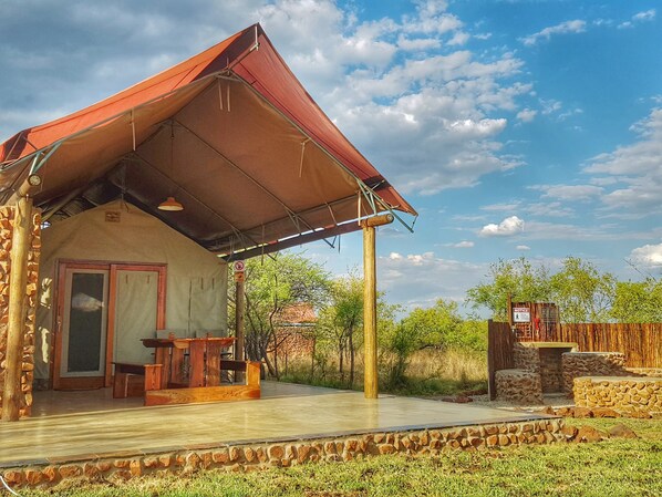 A lodge with a covered patio, a stone wall, and a wooden fence.