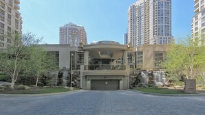 A modern building with a central entrance, surrounded by high-rise residential buildings. - NAPA Furnished Suites Square One (Mississauga)