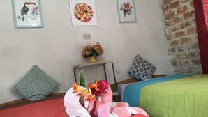 Et værelse med en seng, et lille bord med en vase blomster, og tre billeder hængende på væggen.