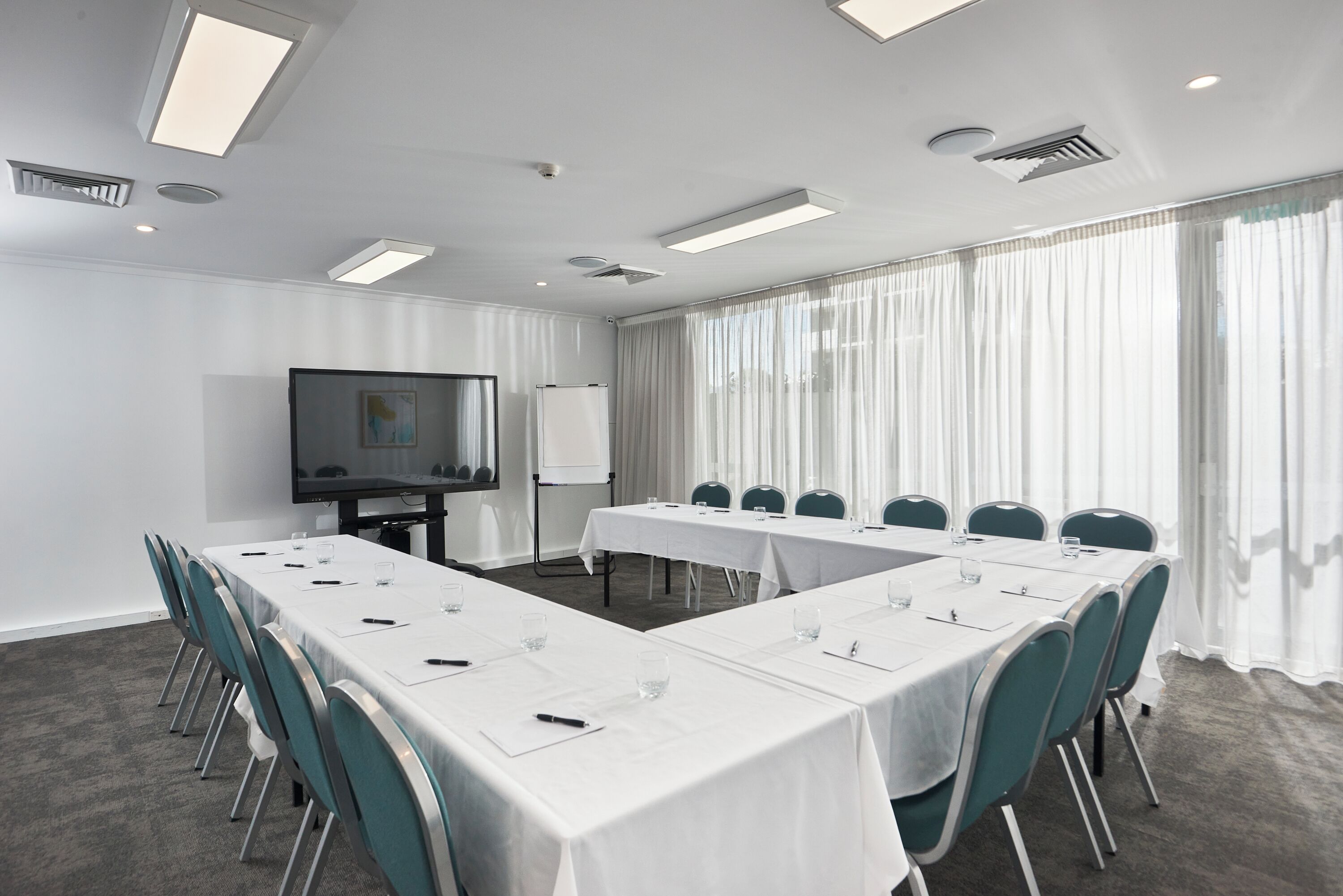 A conference room with a long table, chairs, a projector screen, and a whiteboard.