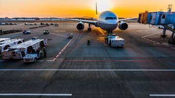 An airport tarmac with an airplane parked, ground crew, and airport service vehicles.