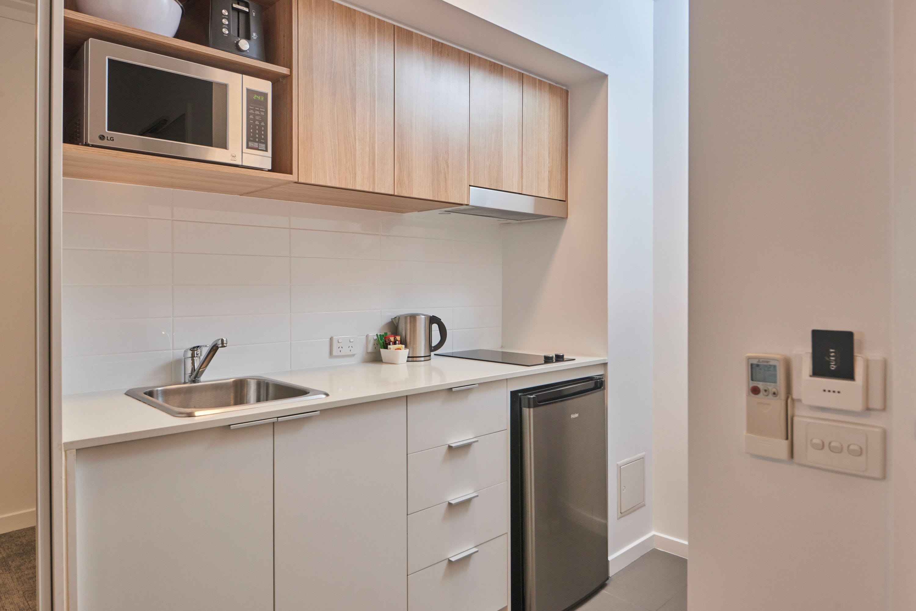 Een moderne keuken met witte kasten, roestvrijstalen apparatuur en een inbouwmagnetron.