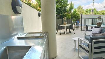 A kitchen area with stainless steel appliances, a white pillar, and outdoor seating with a table and chairs.