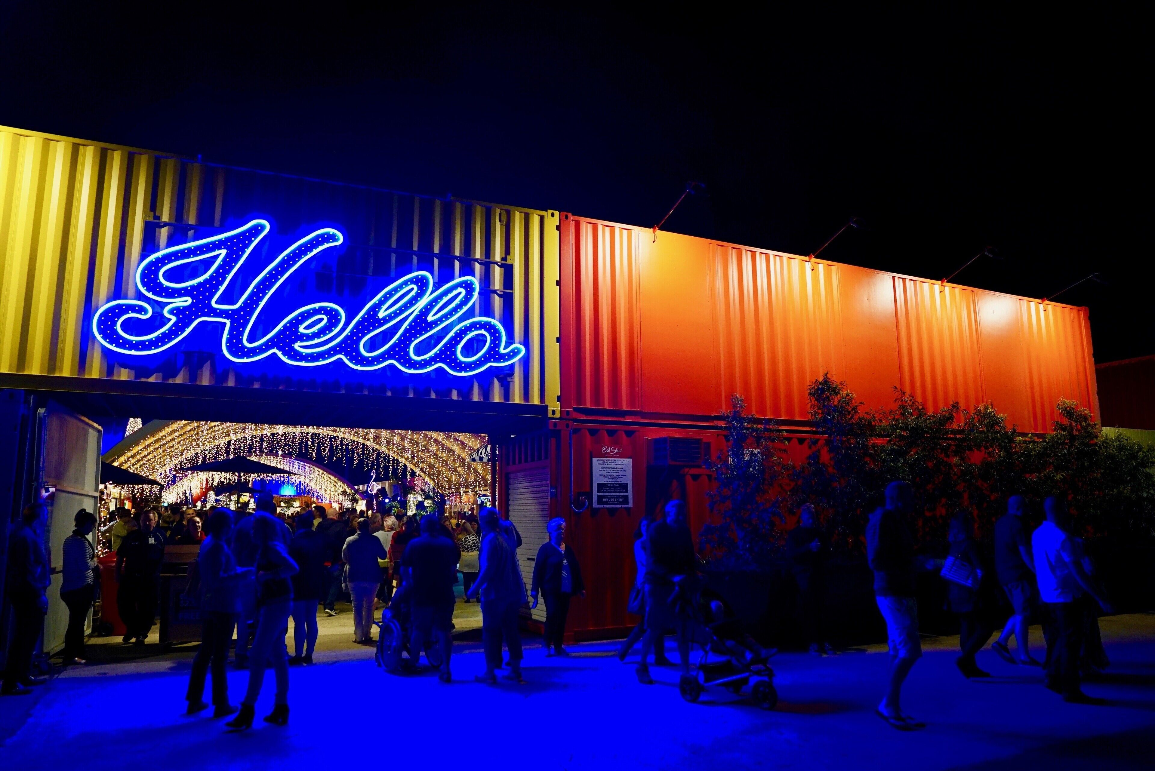 A brightly lit building with a neon 'Hello' sign, indicating a welcoming entrance.