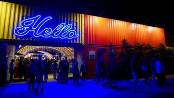 A brightly lit building with a neon 'Hello' sign, indicating a welcoming entrance.