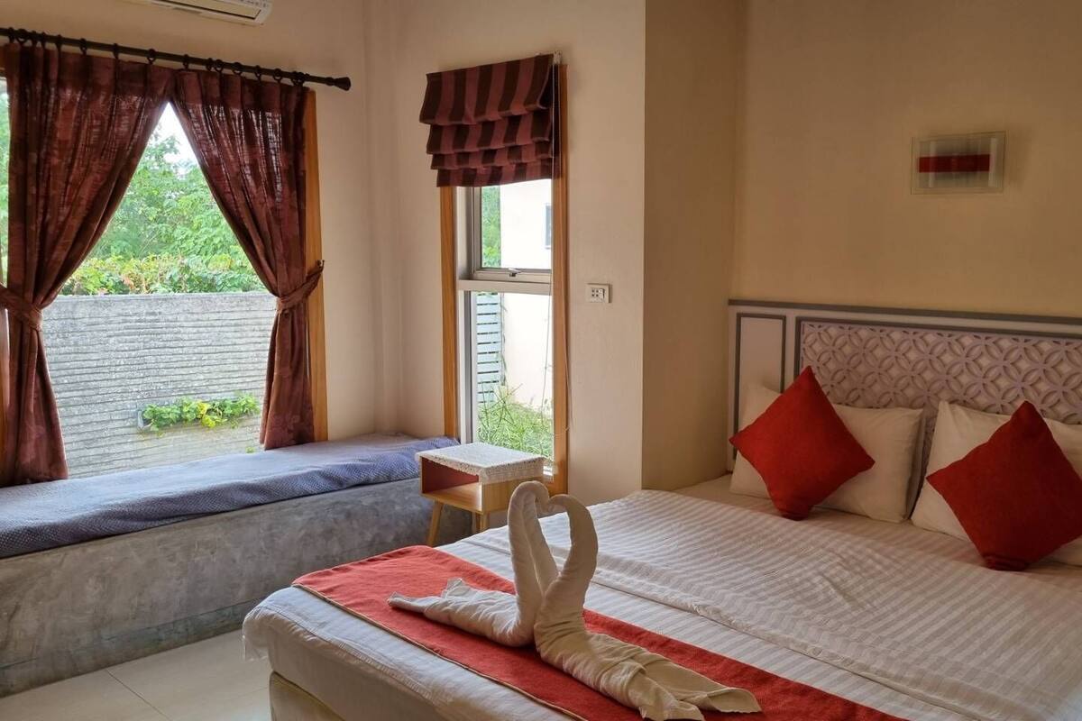 Habitación de hotel con cama, ventana con cortinas, una mesita y vista a espacios verdes.