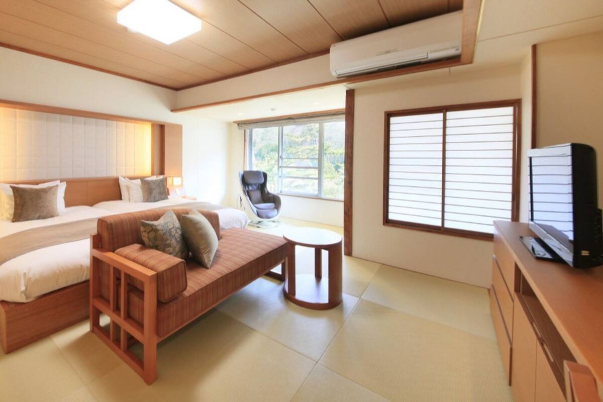 Una habitación de hotel moderna con una cama grande, un sofá, un escritorio y un televisor.