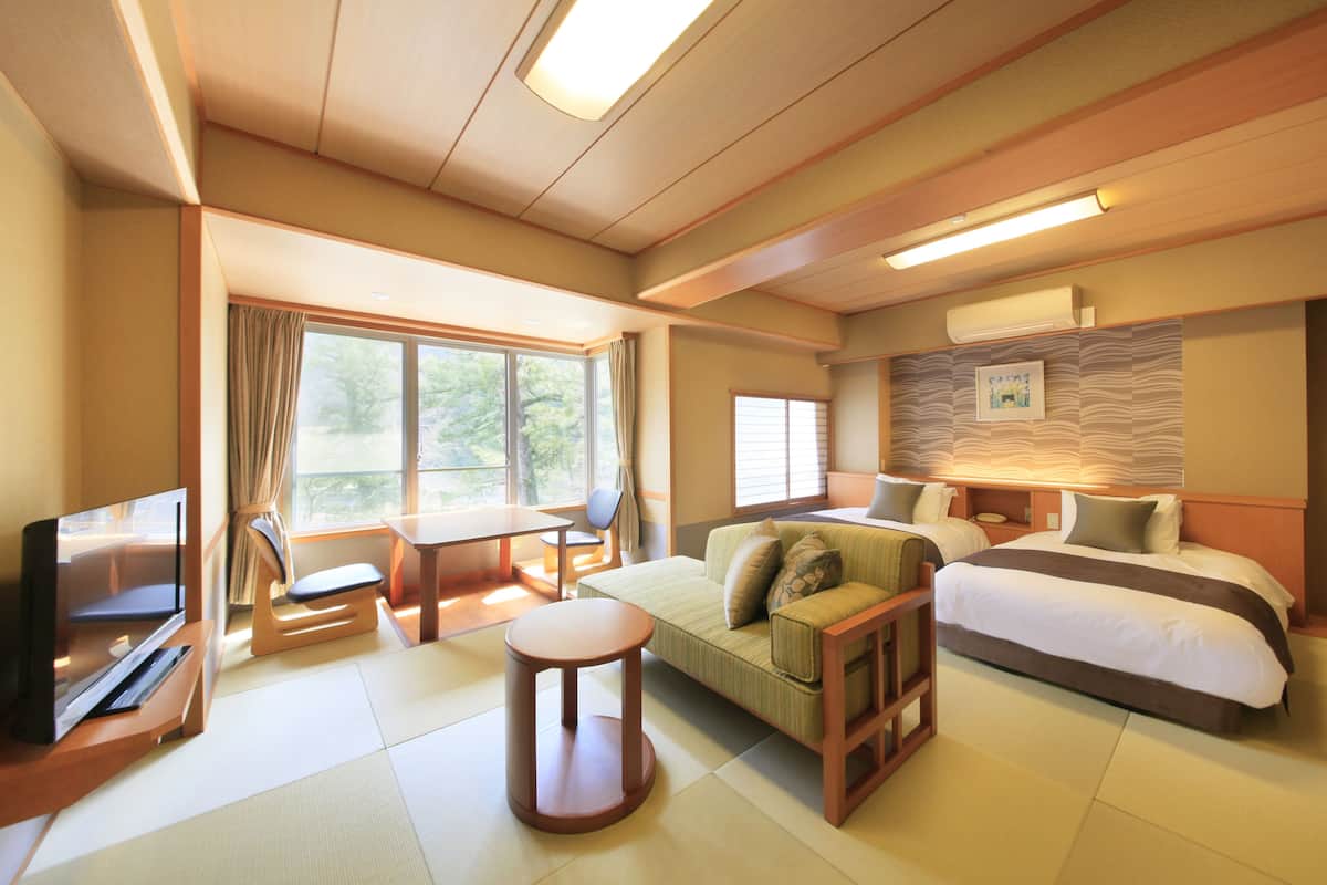 Una habitación de hotel con cama, sofá, televisor y una pequeña mesa.
