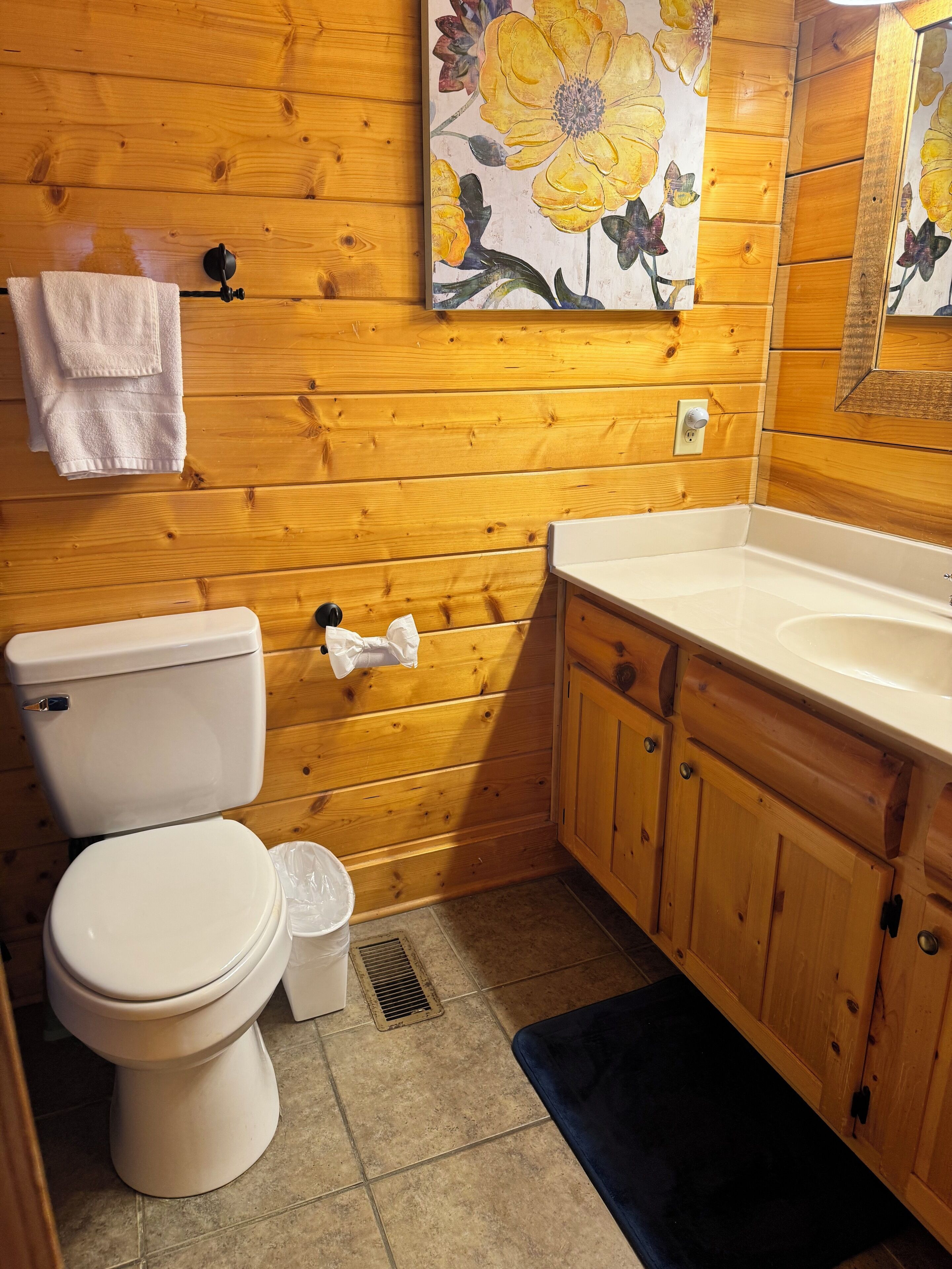 Ein Badezimmer mit Holzwandverkleidung, Toilette, Waschbecken und Schränken.