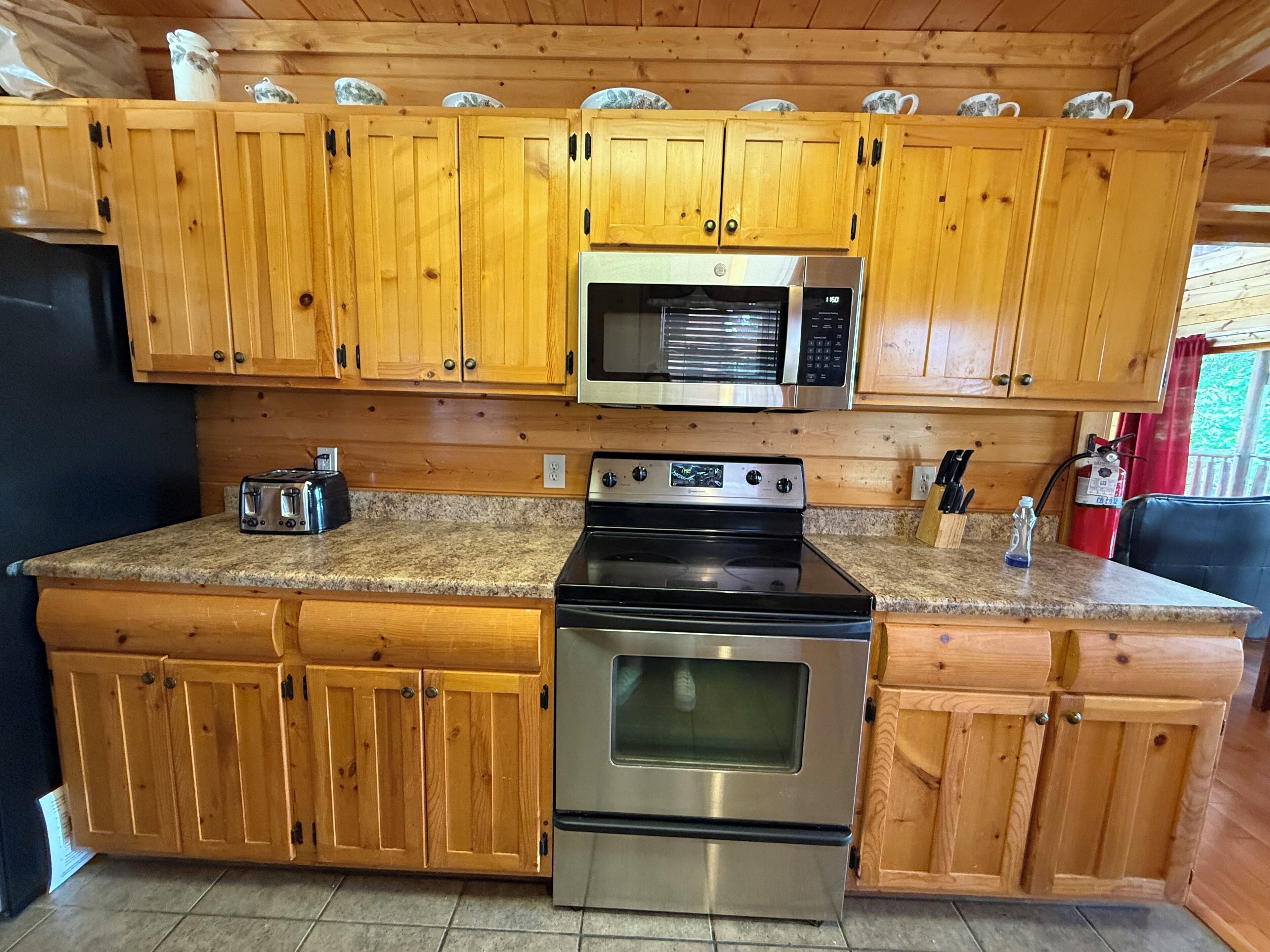 A kitchen with wooden cabinets, a microwave, a stove, and a toaster.