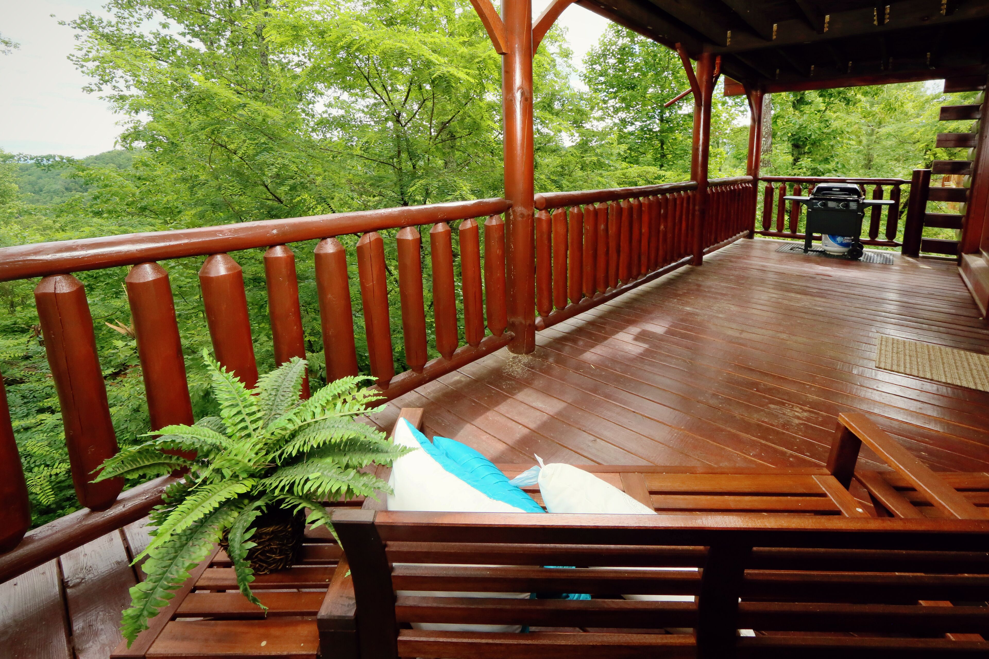 Une terrasse en bois avec une rambarde, un banc et un barbecue.