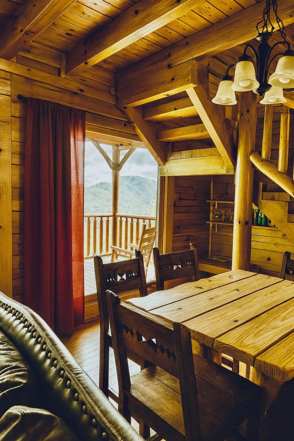 L’intérieur d’un chalet en bois comprend une table à manger, des chaises, un canapé en cuir et un escalier.