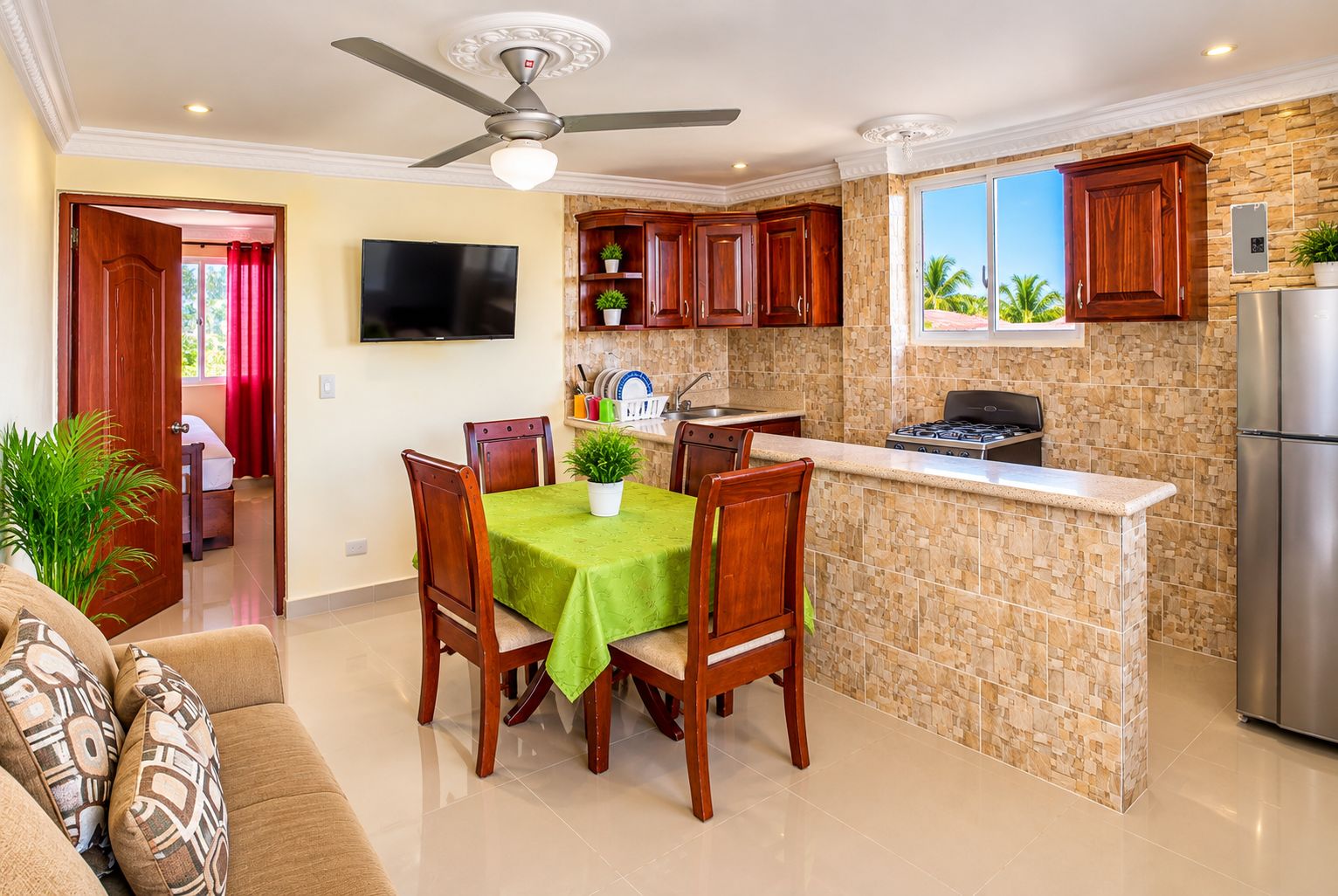 A modern kitchen with a central island, wooden cabinets, a built-in stove, and a stainless steel refrigerator.