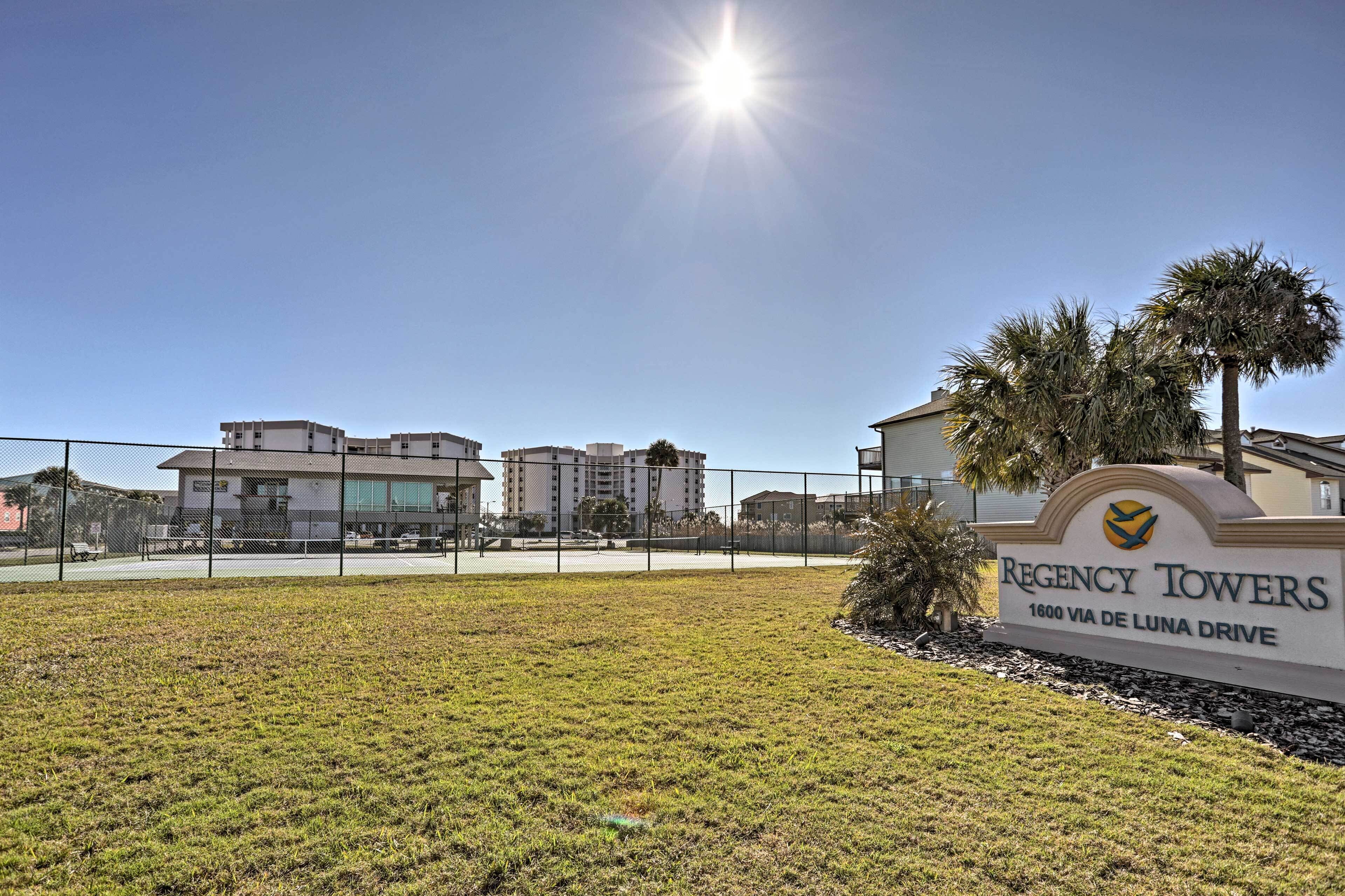 A sign for Regency Towers at 1600 Via de Luna Drive, with a clear sky and a fenced area in the foreground.