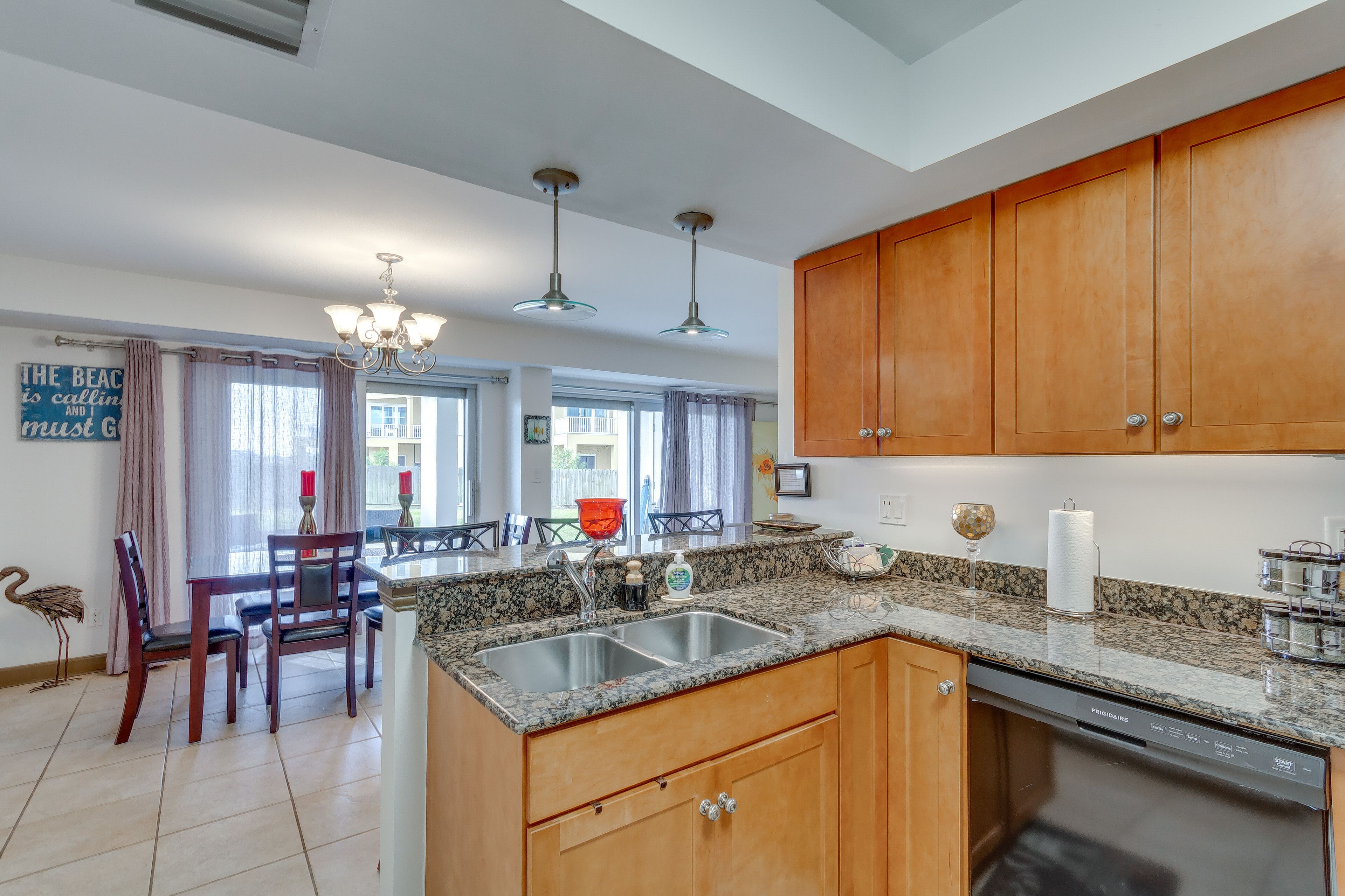 A kitchen with wooden cabinets, a granite countertop, and a built-in dishwasher.