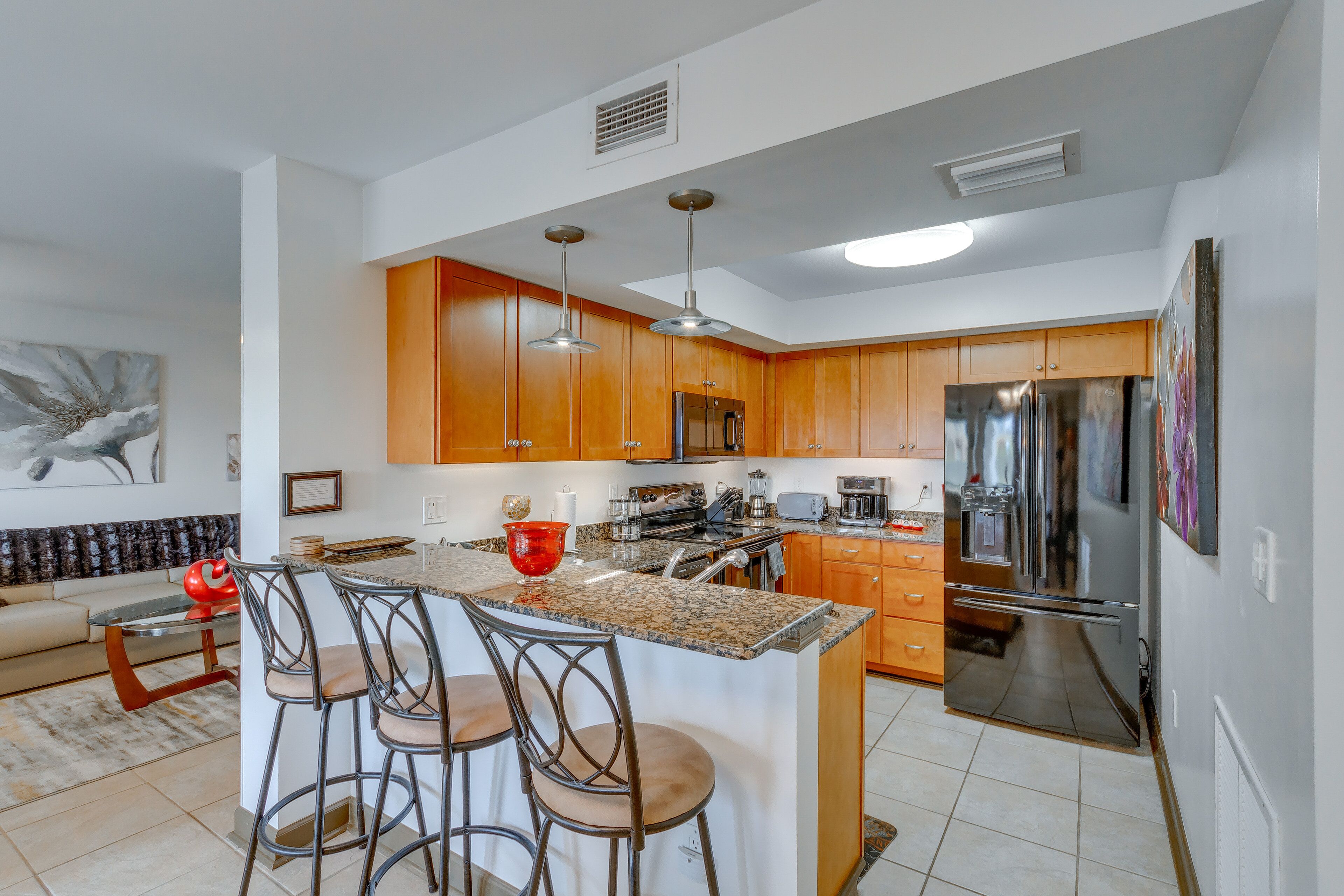 Una cocina moderna con armarios de madera, electrodomésticos de acero inoxidable y una isla central con taburetes de bar.