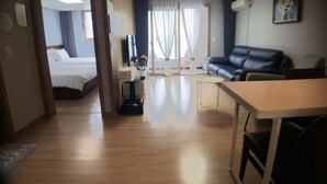 Quarto de hotel com cama, secretária, sofá e vista para o exterior.