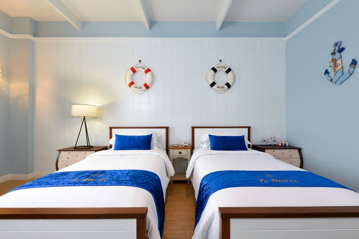 A double room with two beds, each with a blue bedspread and a "Welcome" sign above.