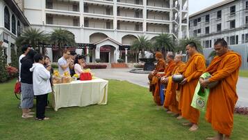 A courtyard with a table set up for a meal, surrounded by people and monks.