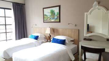 Habitación de hotel con dos camas, un cuadro, un escritorio y un espejo.